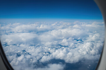 Aerial of snowcapped mountains in eastern Canada under cloudy sky seen through an aiplane window