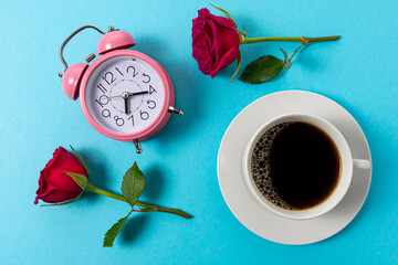 Creative layout made with cup of coffee and alarm clock on blue background. Minimal time concept.