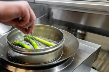 chef cooking steaming green asparagus in a steamer 