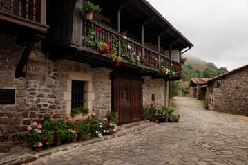 Naklejka premium Traditional mountain stone houses with wooden balconies in a cobblestone street, Barcena Mayor, Saja-Besaya Natural Park, Cantabria, Spain