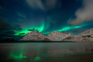 Night sky with northern lights and clouds at Haukland Beach, Lofoten Islands, Norway