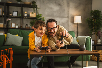 Father and son play video games with joystick and have fun at home © Miljan Živković