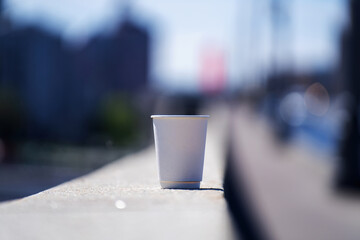 Paper cup on concrete bridge railings with a blurred background