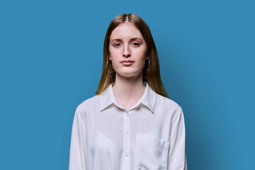 Portrait of teenage smiling female in white shirt on blue background