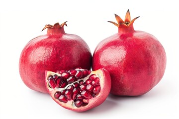 Two pomegranates, one cut open to reveal seeds, with scattered seeds on a surface, next to a textured wall with peeling paint