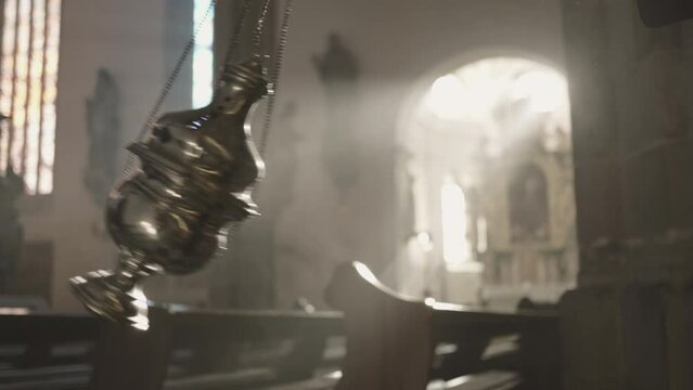 Metal censer swinging on chains in Christian church closeup. Religious incense burning in thurible close up. Worship ritual in cathedral