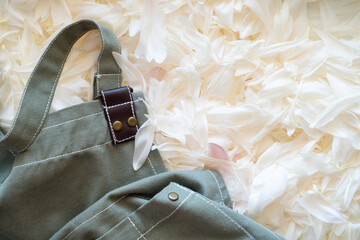 Green apron close-up against a background of flowers. Flowers and florist concept. Flower petals