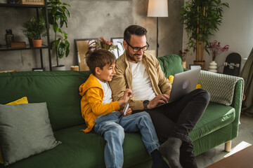 Father and son buy online with credit card on laptop at home