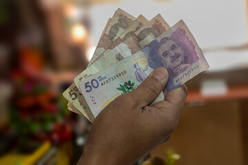 Money from Colombia, Man holding peso bills in front of him, Business investments, Creative...