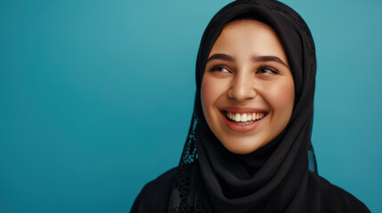 A positive Muslim woman wearing a traditional headscarf smiles happily at the camera