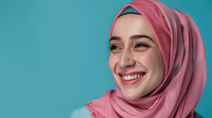 A positive Muslim woman smiling happily while wearing a traditional pink headscarf