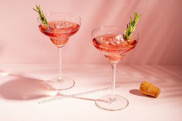 Refreshing cocktail with rosemary in a glass on a bright background. Summer party concept.