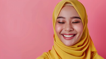 A positive Muslim woman smiles happily while wearing a traditional yellow hijab