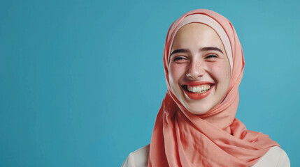 A positive Muslim woman smiles wearing a traditional headscarf, looking directly at the camera