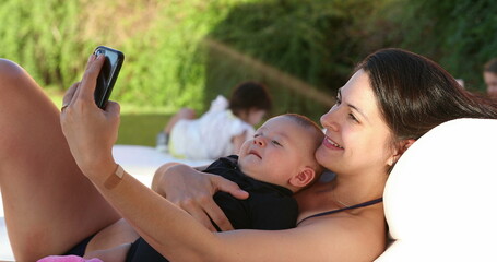 Mom and baby taking selfie together outside by the pool