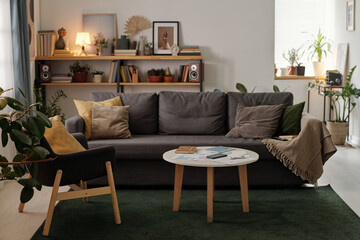 Low round table with mobile gadgets, financial bills and notepad standing in the center of living room against couch with cushions