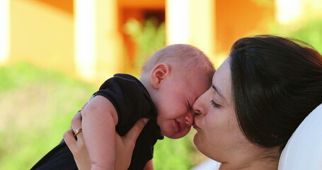 Mom calming crying baby infant outdoors showing love affection and care