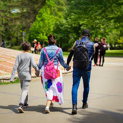 Happy family with son walking and talking in park holding hands