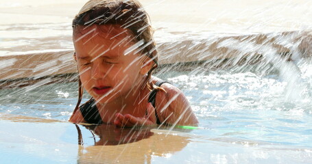 Little girl at the swimming pool water splashing