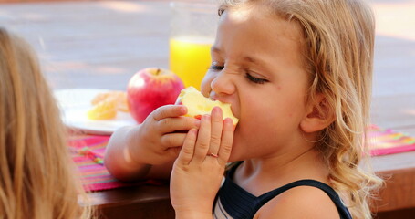 Little girl biting apple eating fruit outside