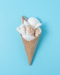 Creative composition with seashells and ice cream cone on pastel blue background. Summer minimal concept.