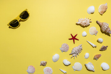Creative composition with seashells and sunglasses on bright yellow background. Summer minimal...