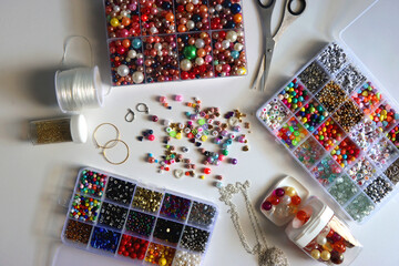 Colorful beads, letter beads, threads and other jewelry making supplies on white background. Making...