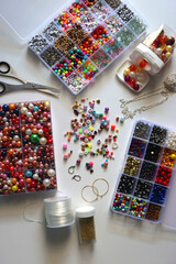 Colorful beads, letter beads, threads and other jewelry making supplies on white background. Making friendship bracelets concept. Flat lay. 