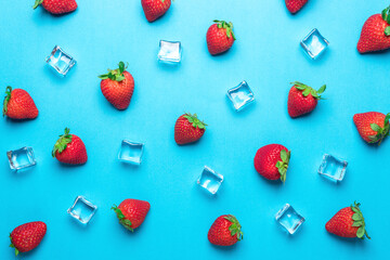 Colorful pattern made of strawberries with ice cubes on blue background. Minimal summer concept.