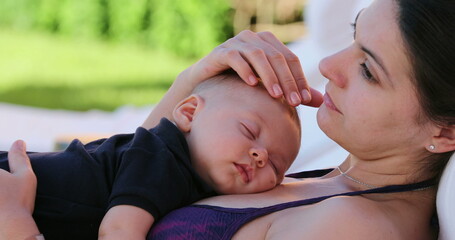 Mother showing love and affection to baby infant while sleeping by the poolside