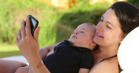 Mother taking selfie with baby infant by the pool