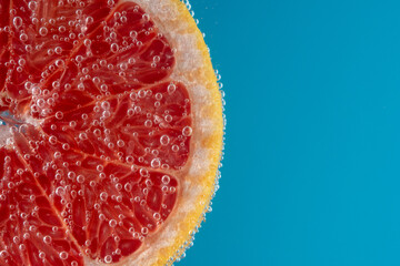 Close up view of a slice of grapefruit in soda water with bubbles. Summer drink concept.