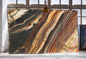 Picture of a backlit onyx slab on a hanger, shot in natural light, a cut of decorative marble in a...