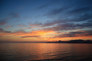Fototapeta premium A beautiful sunset with clouds over the sea and the coastline
