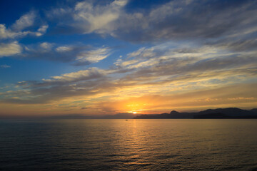 A beautiful sunset with clouds over the sea and the coastline