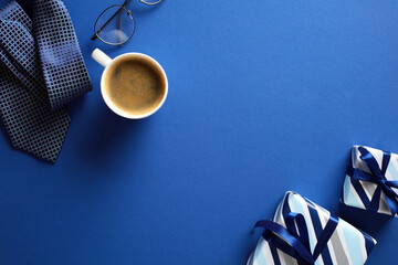 Happy Fathers Day flat lay composition with gift boxes, necktie, cup of coffee, glasses on dark blue background.