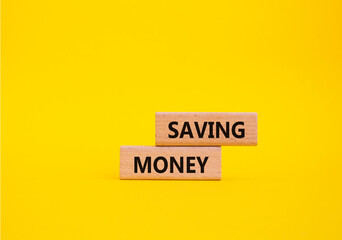 Saving Money symbol. Concept word Saving Money on wooden blocks. Beautiful yellow background....