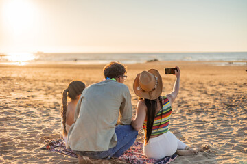 Multicultural Friends Taking Sunset Selfie on Beach Seen from Behind