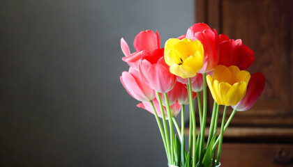 Vibrant bouquet of pink and yellow tulips in a glass vase. Mother's day or women's day background, copy space. Bright tulips in a vase. Elegant bouquet of red and yellow tulips