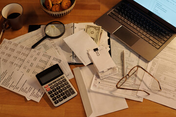 High angle of calculator, envelope with dollar banknotes, magnifying glass, stack of receipts, pen,...