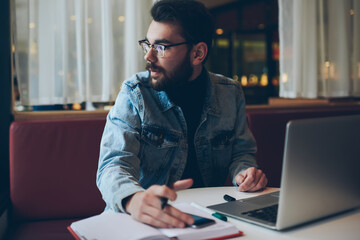 Handsome thoughtful male freelancer looking away working on laptop computer, pensive clever man...