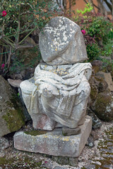 Ancient Roman antique sculpture of a headless man in a seated pose with a tunic thrown over him in a park on the street