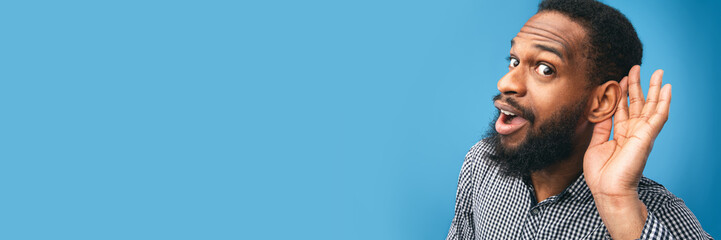 Eavesdropping Concept. Closeup of black guy holding hand near his ear and listening carefully...
