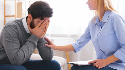 Professional help. Depressed man crying at psychotherapy in despair, psychologist consoling stressed patient