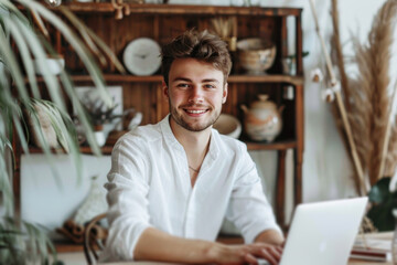 Obraz premium Portrait of a handsome smiling young man using laptop