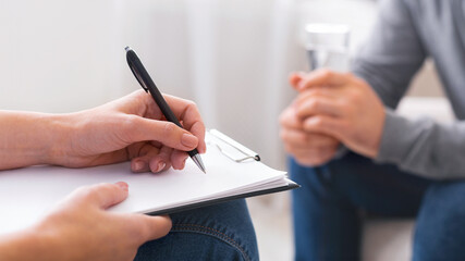 Psychologist taking notes during session with depressed patient, close up, panorama