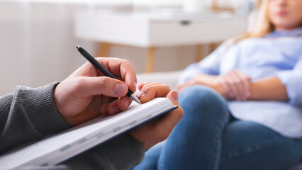 Professional psychotherapist taking notes, listening to female patient problems, panorama