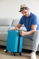 Man closing suitcase at home about to go on vacation
