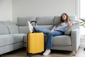 Woman resting on the sofa with travel suitcases prepared