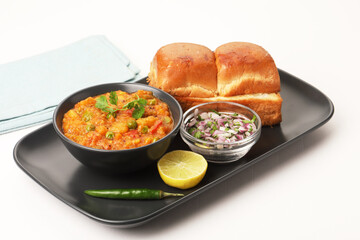 Pav Bhaji is a fast food dish from India, Thick and spicy vegetable curry, fried and served with a soft bread roll/Bun Pav and butter